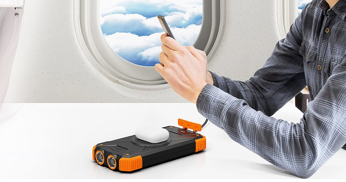 Portable travel power bank with wireless charging on airplane tray table, charging devices mid-flight with compact multi-device setup