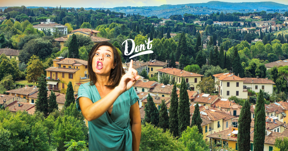 A woman gesturing to the word 'don’t' with the Tuscan countryside in the background, symbolizing travel etiquette in Tuscany.