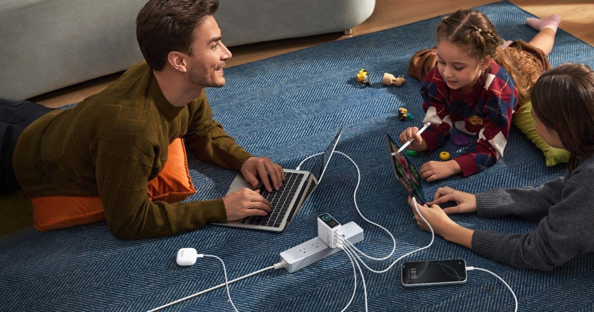 Anker 140W 4-Port USB-C GaN Charger with digital status screen, charging a MacBook and iPhone simultaneously for seamless travel.