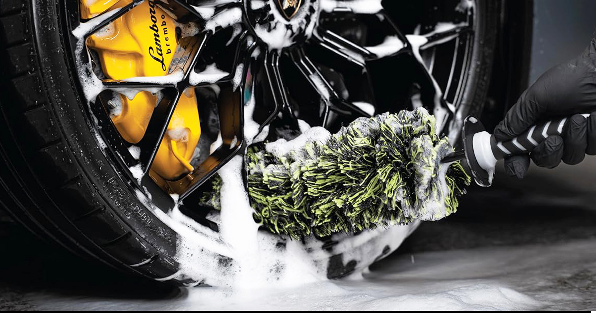 Close-up of the VIKING Multi-Fiber Car Cleaning Brush scrubbing a luxury alloy wheel covered in foam, reaching deep into the rim to remove brake dust, dirt, and grime for a spotless finish.