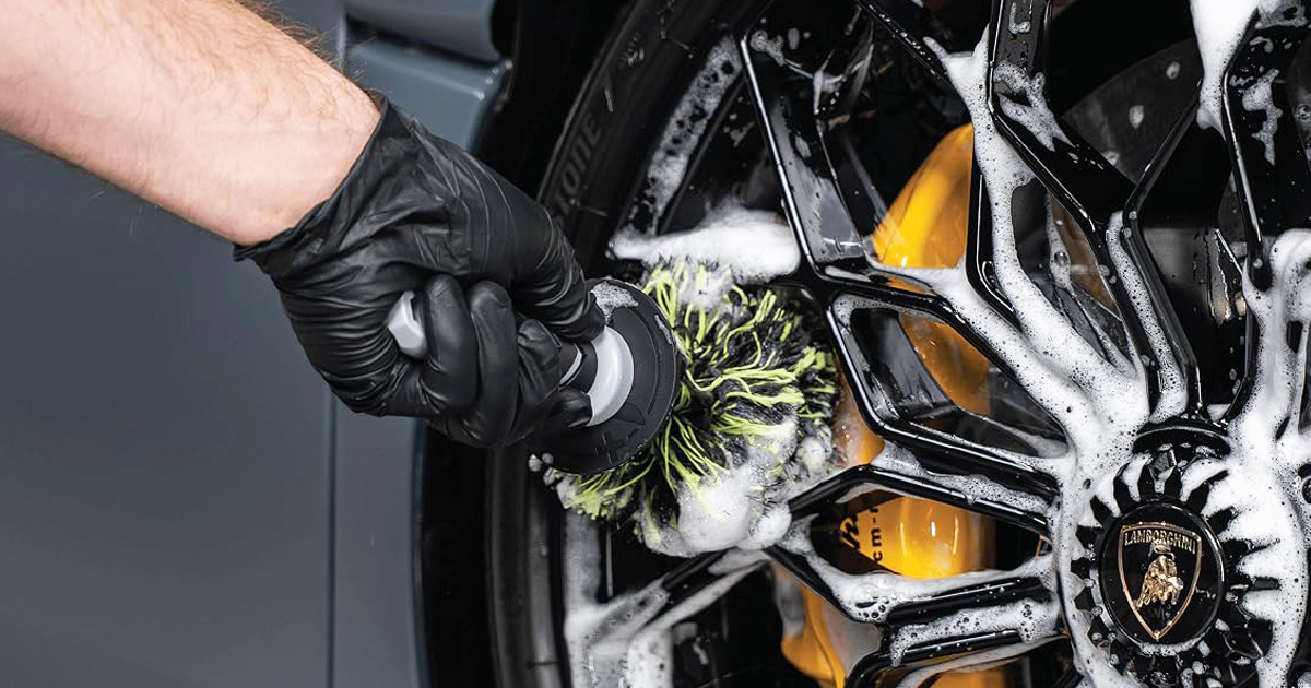 Close-up of the VIKING Multi-Fiber Car Cleaning Brush scrubbing a luxury alloy wheel covered in foam, reaching deep into the rim to remove brake dust, dirt, and grime for a spotless finish.