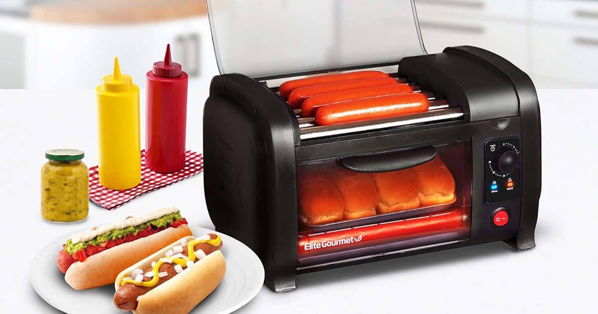 Elite Gourmet hot dog toaster and bun warmer with grill rollers, featuring four hot dogs cooking on top and buns warming inside, served alongside condiments.