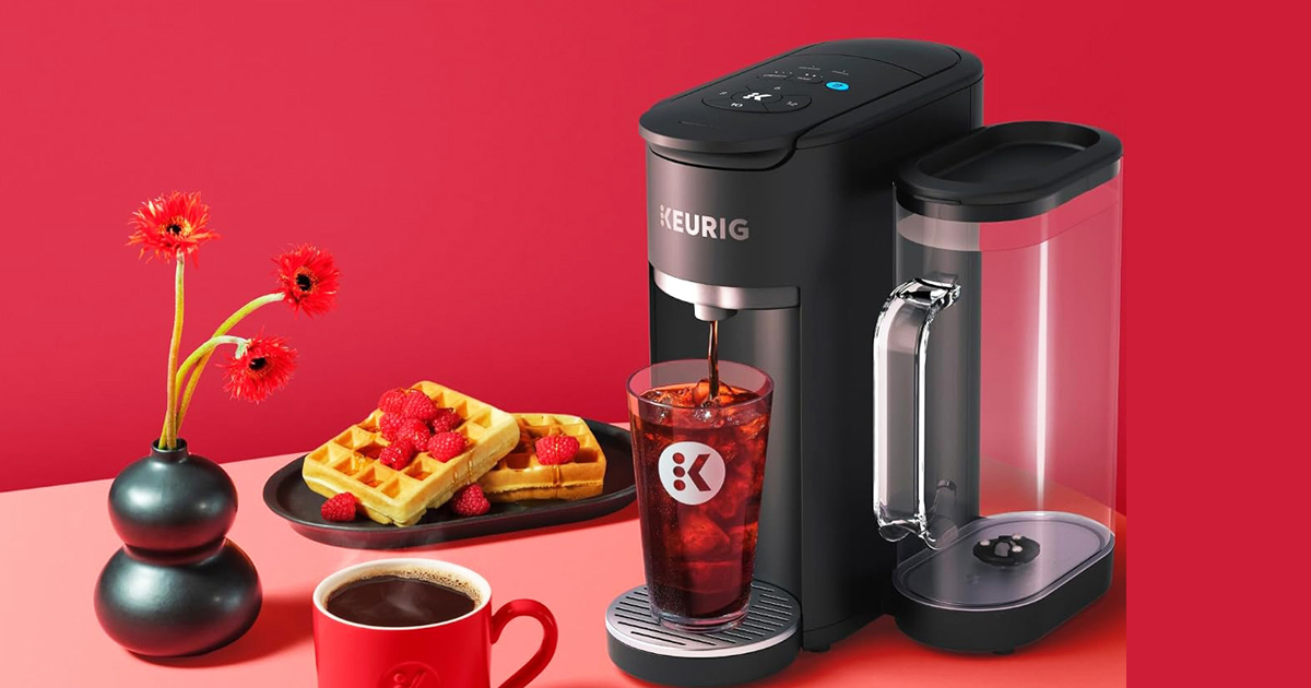Matte black Keurig K-Supreme Gen 2 coffee maker brewing iced coffee next to a red mug and waffles.