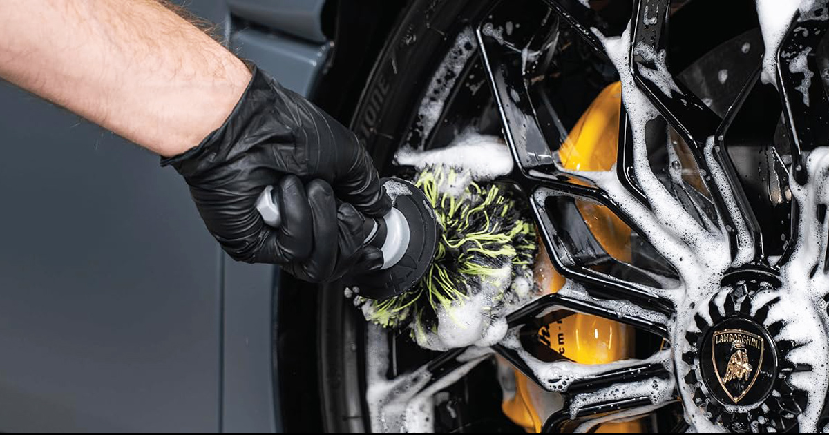 Close-up of the VIKING Multi-Fiber Car Cleaning Brush scrubbing a luxury alloy wheel covered in foam, reaching deep into the rim to remove brake dust, dirt, and grime for a spotless finish.